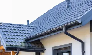 Szary dach z dachówki ceramicznej, z rynnami i kominem. Sprawdź aktualną dachówka ceramiczna cena za m2.