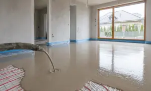 Wylewanie płynnego jastrychu na matę grzewczą w nowym domu.