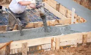 Betoniarka wylewa beton do drewnianej formy, tworząc wylewkę.