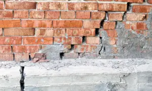 Uszkodzona ceglana ściana i pęknięty betonowy stopień świadczą o problemach z podbijaniem fundamentów.