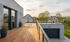 Drewniany taras nad garażem z leżakiem i widokiem na wieś.