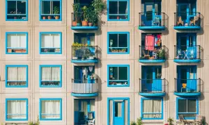 Elegancka loggia i balkon z niebieskimi ramami okiennymi, pełne zieleni i suszącego się prania, tworzą barwną fasadę budynku.