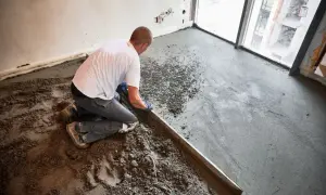 Budowlaniec wyrównuje wylewkę z **anhydrytu** za pomocą łaty.