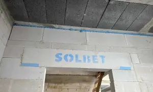 Ściana z bloczków z widocznym logo "SOLBET" i niebieską pianką montażową, która zapobiega pękaniu i zapewnia dylatację.