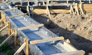 Szalunek betonowy z folią i drewnianymi wspornikami na budowie fundamentów.
