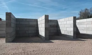 Budowa muru oporowego z bloczków betonowych. Zbrojenie widoczne na górze ścian.