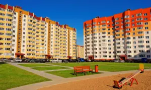 Nowe bloki z wielkiej płyty w kolorach żółtym i pomarańczowym, z parkingiem i placem zabaw.