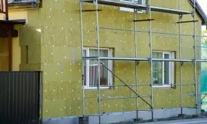Dom w trakcie termomodernizacji, ocieplany wełną mineralną. Widać rusztowania i fragmenty starego muru pruskiego.
