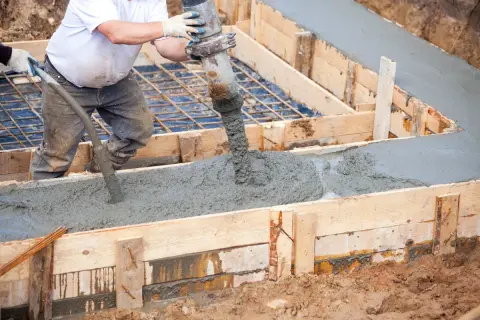 Betoniarka wylewa beton do drewnianej formy, tworząc wylewkę.