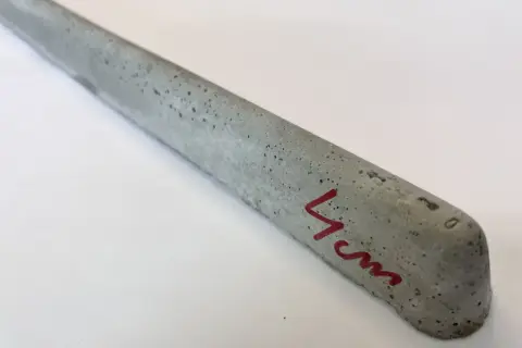 Szary, betonowy element z widocznymi pęcherzykami powietrza, oznaczony czerwonym markerem "4cm". To dystanse do zbrojenia betonowego.