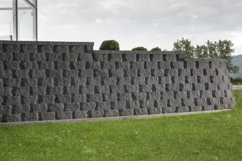 Nowoczesny pomysł na murek oporowy z szarego kamienia, idealny do ogrodu.