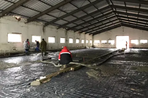 Pracownicy wylewają beton na siatkę zbrojeniową. Czekamy, aż wylewka schnie, by móc kontynuować prace.