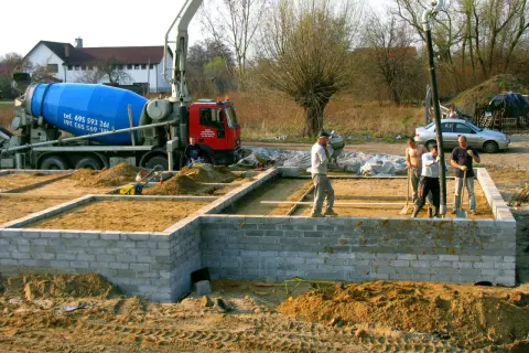 Budowa fundamentów: betonowóz i ekipa przygotowują teren. Czym obsypać fundamenty? Piaskiem i żwirem.
