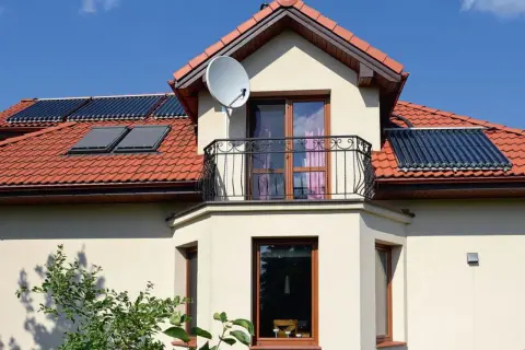 Elegancki wykusz co to? To część domu wystająca na zewnątrz, z oknami i balkonem, na dachu kolektory słoneczne.