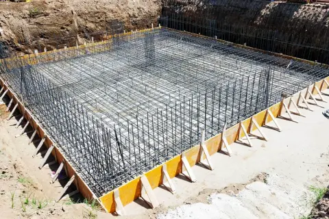 Siatka zbrojeniowa ławy fundamentowej w wykopie, przygotowana do zalania betonem.