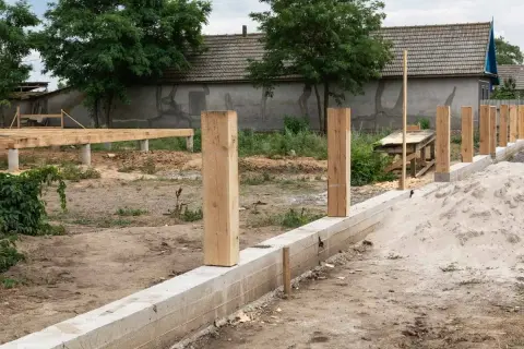 Budowa ogrodzenia: betonowy fundament i drewniane słupki czekają na dalsze prace. Jaki fundament pod ogrodzenie jest najlepszy?
