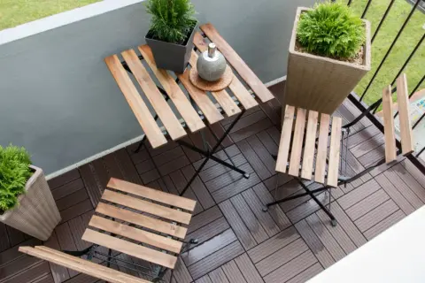 Drewniane deski na balkonie tworzą przytulną przestrzeń. Idealne, by zastanowić się, czym wyłożyć balkon, tworząc miejsce do relaksu.