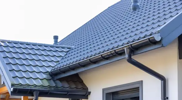 Szary dach z dachówki ceramicznej, z rynnami i kominem. Sprawdź aktualną dachówka ceramiczna cena za m2.