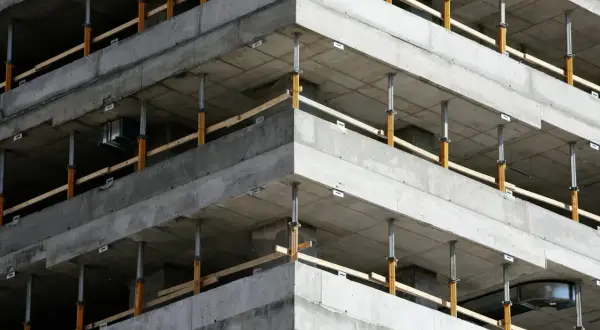 Budowa budynku z betonowymi stropami i zbrojeniem narożników wieńca, podparte tymczasowymi podporami.