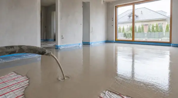 Wylewanie płynnego jastrychu na matę grzewczą w nowym domu.