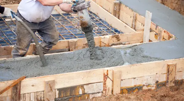 Betoniarka wylewa beton do drewnianej formy, tworząc wylewkę.