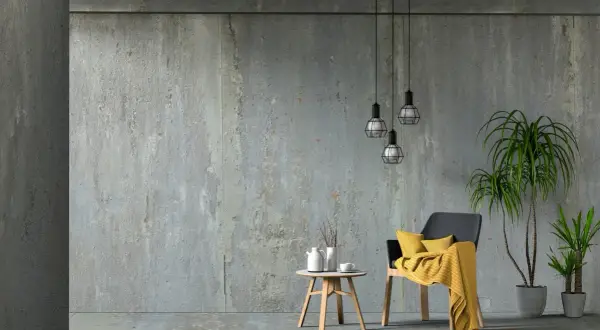 Beton architektoniczny w nowoczesnym wnętrzu. Krzesło z żółtym kocem, stolik z dzbankiem i filiżanką, rośliny.