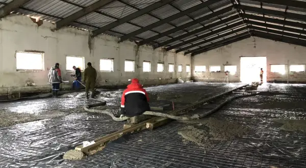 Pracownicy wylewają beton na siatkę zbrojeniową. Czekamy, aż wylewka schnie, by móc kontynuować prace.