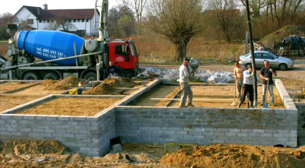 Budowa fundamentów: betonowóz i ekipa przygotowują teren. Czym obsypać fundamenty? Piaskiem i żwirem.