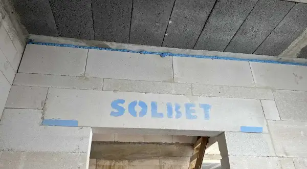Ściana z bloczków z widocznym logo "SOLBET" i niebieską pianką montażową, która zapobiega pękaniu i zapewnia dylatację.