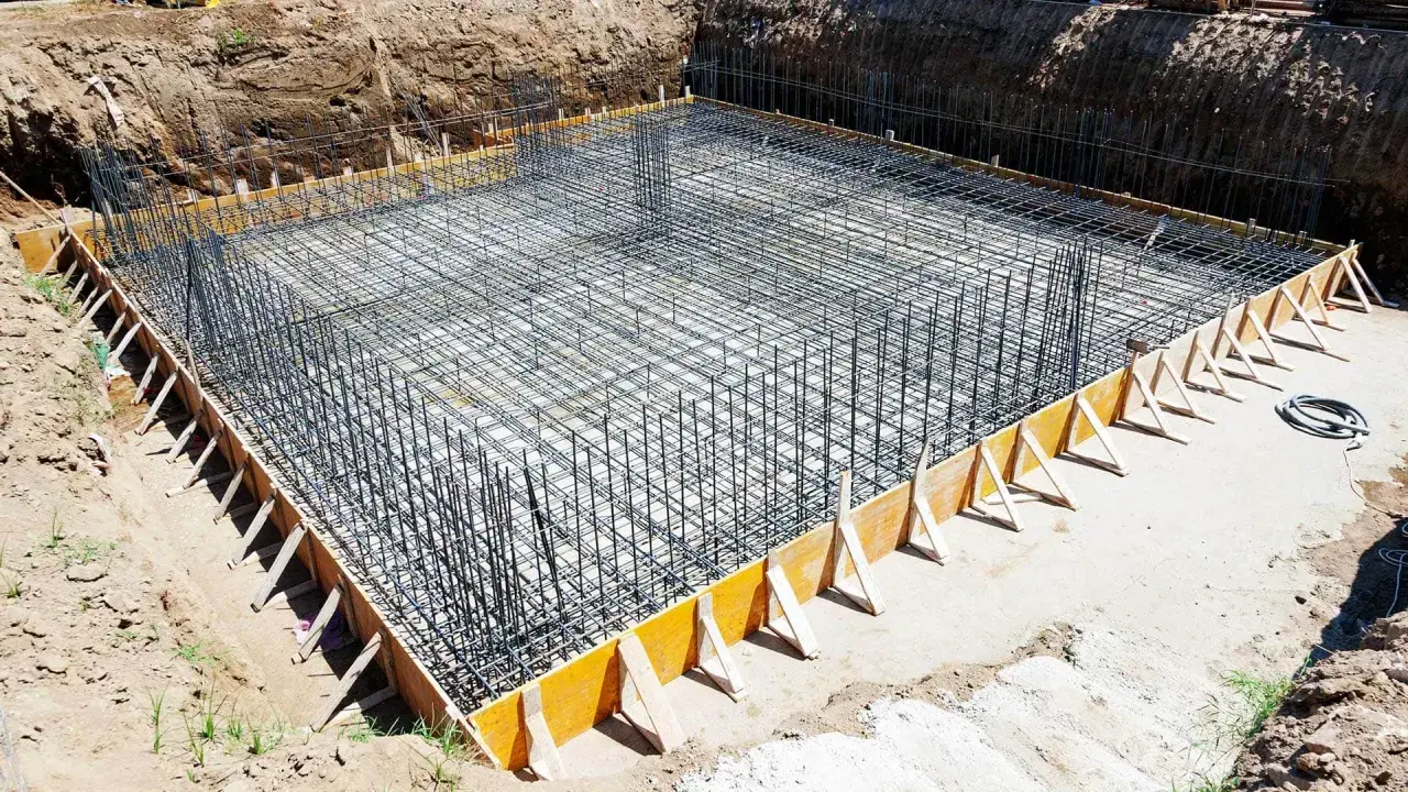 Siatka zbrojeniowa ławy fundamentowej w wykopie, przygotowana do zalania betonem.