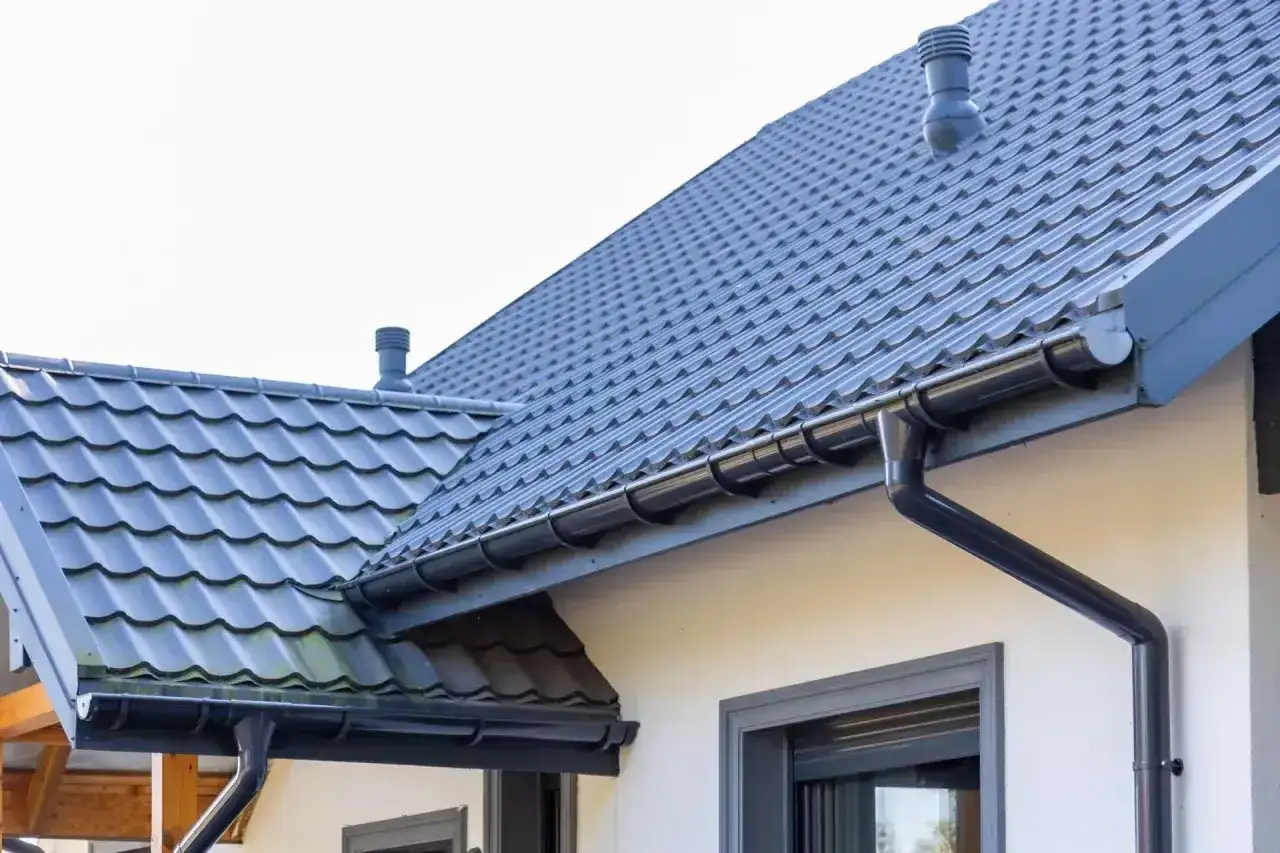 Szary dach z dachówki ceramicznej, z rynnami i kominem. Sprawdź aktualną dachówka ceramiczna cena za m2.