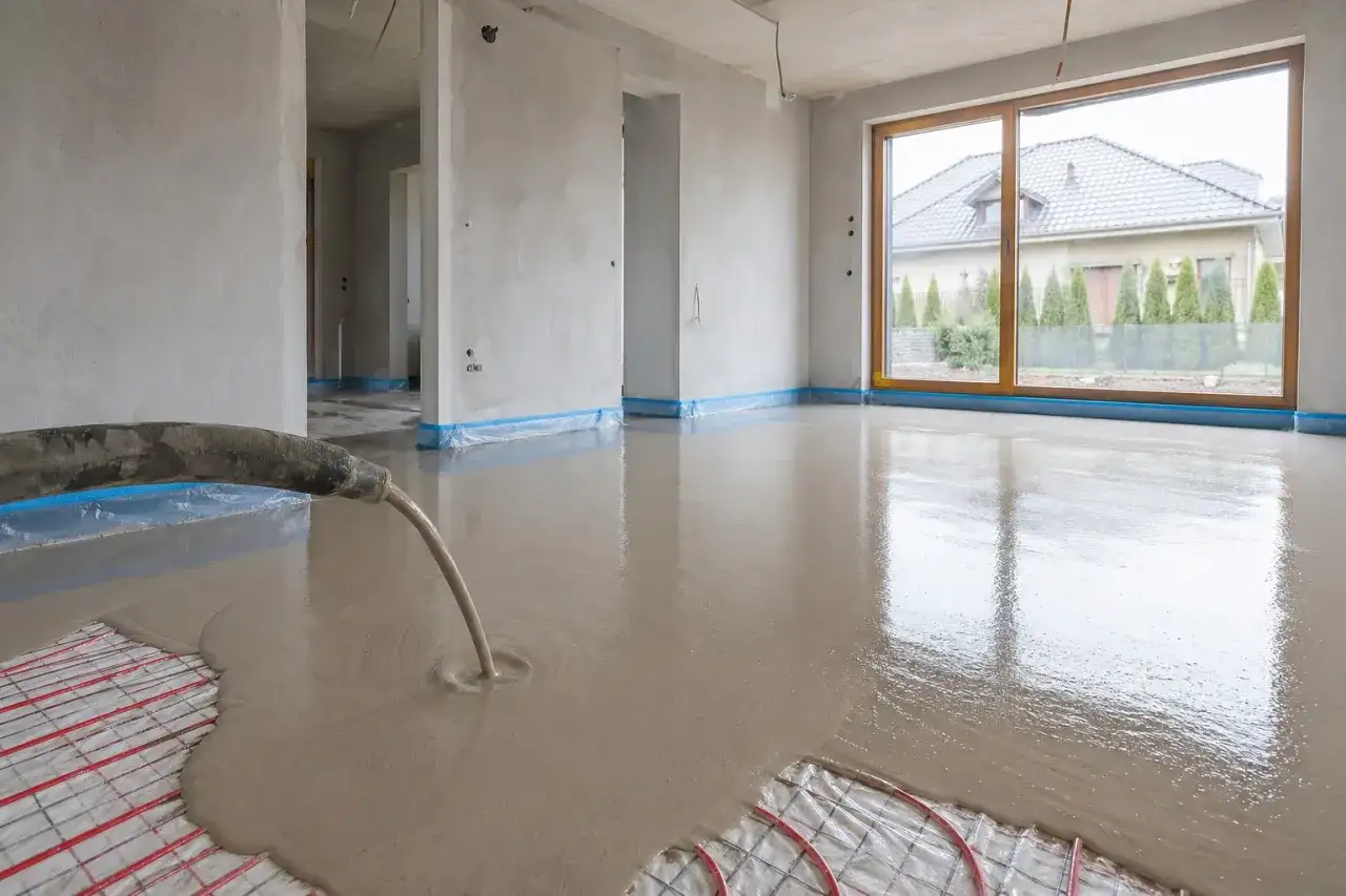 Wylewanie płynnego jastrychu na matę grzewczą w nowym domu.
