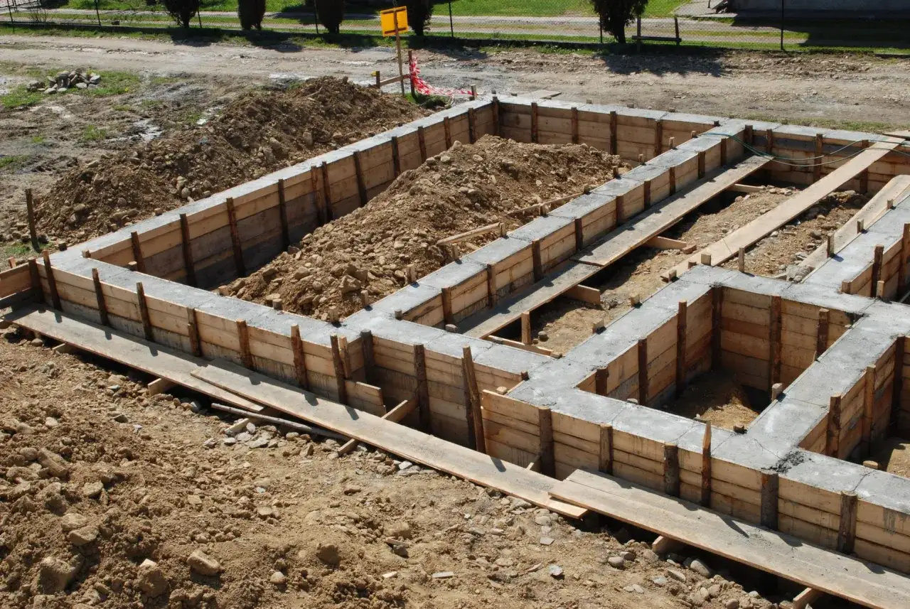Fundamenty domu 100m2 w trakcie budowy. Widać szalunki i wylany beton.
