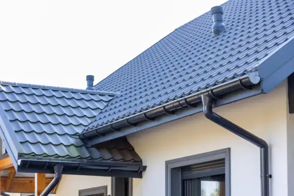 Szary dach z dachówki ceramicznej, z rynnami i kominem. Sprawdź aktualną dachówka ceramiczna cena za m2.