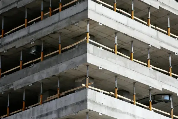 Budowa budynku z betonowymi stropami i zbrojeniem narożników wieńca, podparte tymczasowymi podporami.