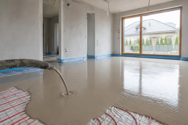 Wylewanie płynnego jastrychu na matę grzewczą w nowym domu.