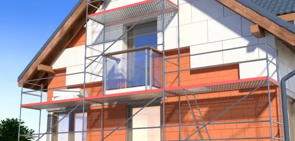 Dom w trakcie ocieplania styropianem, widoczne rusztowanie i fragment elewacji.