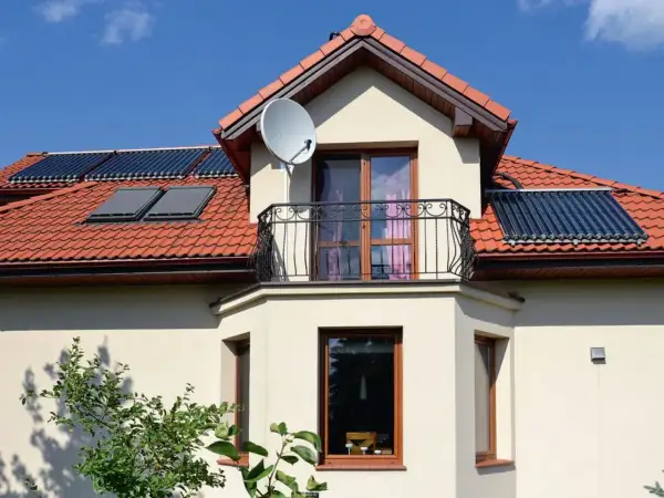 Elegancki wykusz co to? To część domu wystająca na zewnątrz, z oknami i balkonem, na dachu kolektory słoneczne.