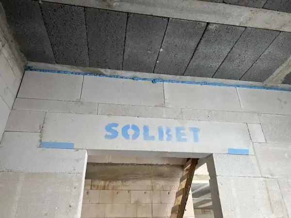 Ściana z bloczków z widocznym logo "SOLBET" i niebieską pianką montażową, która zapobiega pękaniu i zapewnia dylatację.